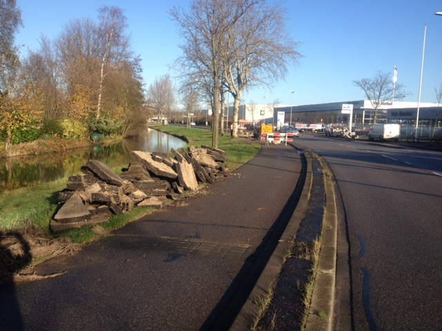 Werkzaamheden aan het fietspad van de Hervensebaan. Omhoogkomende boomwortels zorgden voor overlast. Het asfalt is opengebroken. De losse brokken liggen langs de kant.