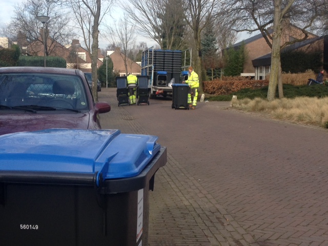 Medewerkers van de gemeente brengen vrijdag de nieuwe papiercontainers rond in De Herven.